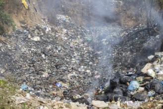 Coking rubbish dump, rubbish pit with waste and plastic rubbish, karst landscape near Vang Vieng,