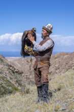 Traditional Kyrgyz eagle hunter with eagle in the mountains, near Kysyl-Suu, Kyrgyzstan, Asia