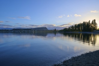 Clear lake with trees on the shore, sunrise and cloudy sky, calm scenery, summer, Lake Wanaka,