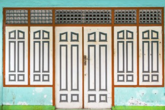 Closed, dilapidated building with peeled off house wall in turquoise colour, pastel, green,