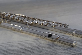 Silver transverse flute with keys on a beige background