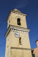 Yellow stucco cladded bell tower with white and black clock face in late summer, Manarola village,