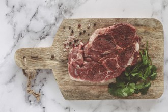 Raw pork steak, pork neck, on a chopping board, marble table, top view, with spices and coriander,