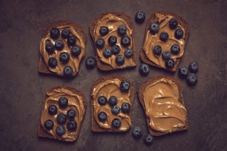 Rye bread with peanut paste and fresh blueberries, top view, no people