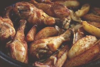 Fried chicken drumsticks with potato slices, in a clay pan, baked in the oven, with spices,