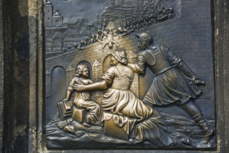 Bronze relief, Saint Nepomuk falling over the bridge, laying hands on the relief in the pillar is