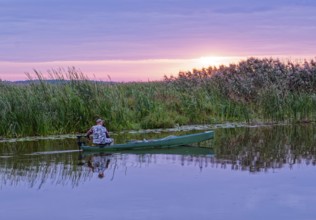 A fisherman in his boat in the early morning on a side arm of the Narew in the Narew National Park