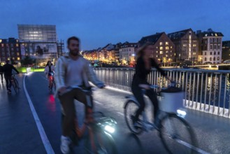 Cyclists on the Inderhavnsbroen cycle and footpath bridge, across the harbour, at night, at Nyhavn,