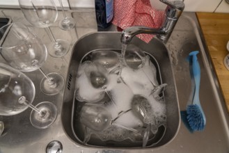 Kitchen after a big dinner, cooking party, sink with dirty glasses, sink