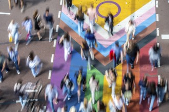 People crossing a pedestrian crossing, on a road, the road surface is colourful, in rainbow