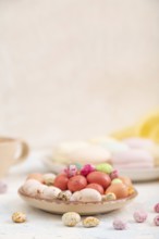 Colored dregees with cup of coffee on white concrete background and yellow textile. Side view, copy