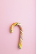 Single cane candy on pink pastel background. copy space, top view, flat lay