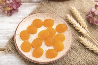 Jelly pumpkin candies on white wooden background and linen textile. selective focus, close up, side