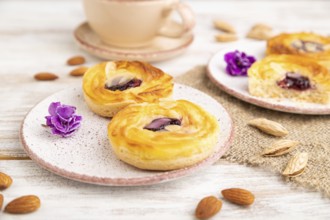 Small cheesecakes with jam and almonds with cup of coffee on a white wooden background and linen