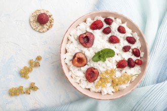 Rice flakes porridge with milk and strawberry in ceramic bowl on white concrete background and blue