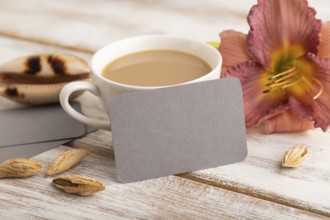 Gray paper business card mockup with purple day-lily flower and cup of coffee on white wooden