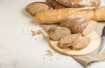 Sliced bread with different kinds of fresh baked bread on a white wooden background. side view,