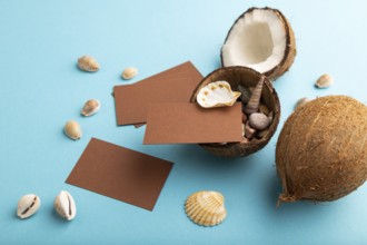 Brown paper business card with coconut and seashells on blue pastel background. Side view, copy