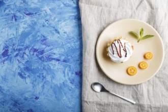 Cake with whipped egg cream on a light brown plate with kumquat slices and mint leaves on a blue