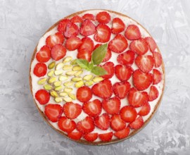 Homemade cake with yoghurt cream, strawberry and pistachio on a gray concrete background. top view.