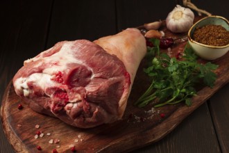 Raw pork knuckle, on a wooden chopping board, with spices, close-up, top view, no people