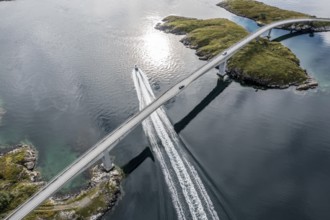 Aerial view of bridge connecting islands at the norwegian coast, motor boat below the bridge,