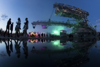 Festival visitors walk under one of the excavators at the Melt Festival in Ferropolis on 13 July