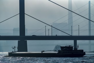 Dense fog slowly lifting, cargo ships on the Rhine near Düsseldorf, in front the Oberkassler