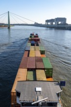 Container cargo ship on the Rhine, heading south, the crane houses in Cologne at the