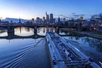 Skyline of the city centre of Frankfurt am Main, river Main, dusk, Ignatz-Bubis-Bridge, cargo ship,