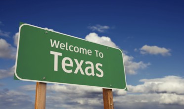 Welcome to texas green road sign over blue sky with some clouds