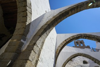 Stone arch and bell tower on a sunny day, Part of a medieval monastery with white walls, Inside the