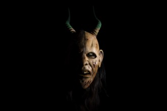 Devilish mask with horns and a terrifying expression in a gloomy atmosphere