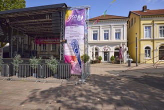 Stage with programme for the 900th anniversary celebrations and pastel-coloured houses with pointed