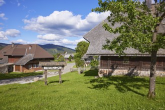 Road with sign to the Resenhof Farm Museum under a blue sky with cumulus clouds in the Oberlehen