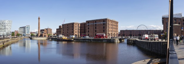 Panorama of the docks with brick buildings and a Ferris wheel on a clear day, Liverpool