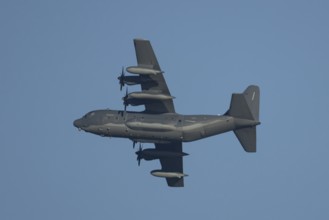 Lockheed C-130 Hercules military aircraft of the USAF United States air force flying in a blue sky,