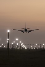 Boeing 737 jet passenger aircraft on approach to land at sunset over landing lights, London