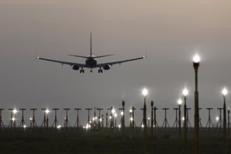 Boeing 737 jet passenger aircraft on approach to land at dusk over landing lights, London Stansted