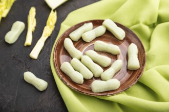 Jelly celery candies on black concrete background and green linen textile. close up, side view,