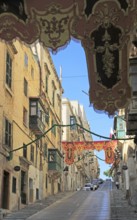 Flags decorate steep historic street in city centre of Valletta, Malta, Europe