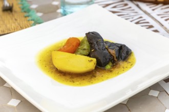 Tagine dish on white plate with potato carrot aubergine courgette and beef, Morocco, north Africa,