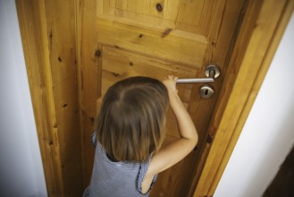 Symbolic photo: A small child tries to open a locked door. Berlin, 21.08.2024