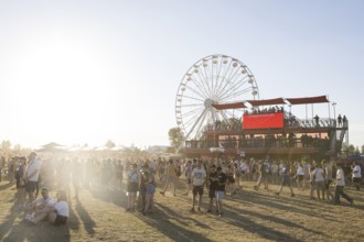 Festival visitors in front of the Ferris wheel and the vantage point of a tobacco vendor at the