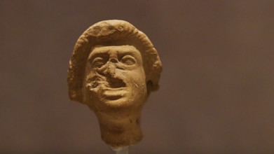 Theatre mask, statuette of a human face made of clay with accentuated facial expressions,