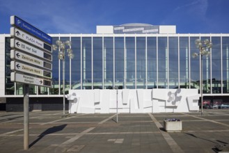 Front of the Musiktheater im Revier in front of a blue sky with lanterns and signs of the parking