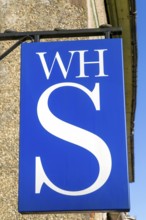 Close up of WH Smith brand logo sign mounted on wall, Hungerford, Berkshire, UK