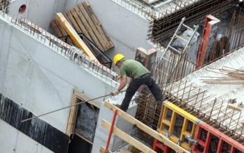 A construction worker juggles with an iron bar in his hand on a building site at lofty heights,