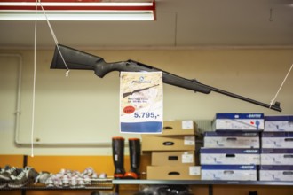 Hunting rifle hanging in supermarket with price tag, Inuit settlement Ittoqqortoormiit,