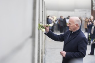 Kai Wegner (Governing Mayor of Berlin) sticks a rose into the Wall at the central commemorative